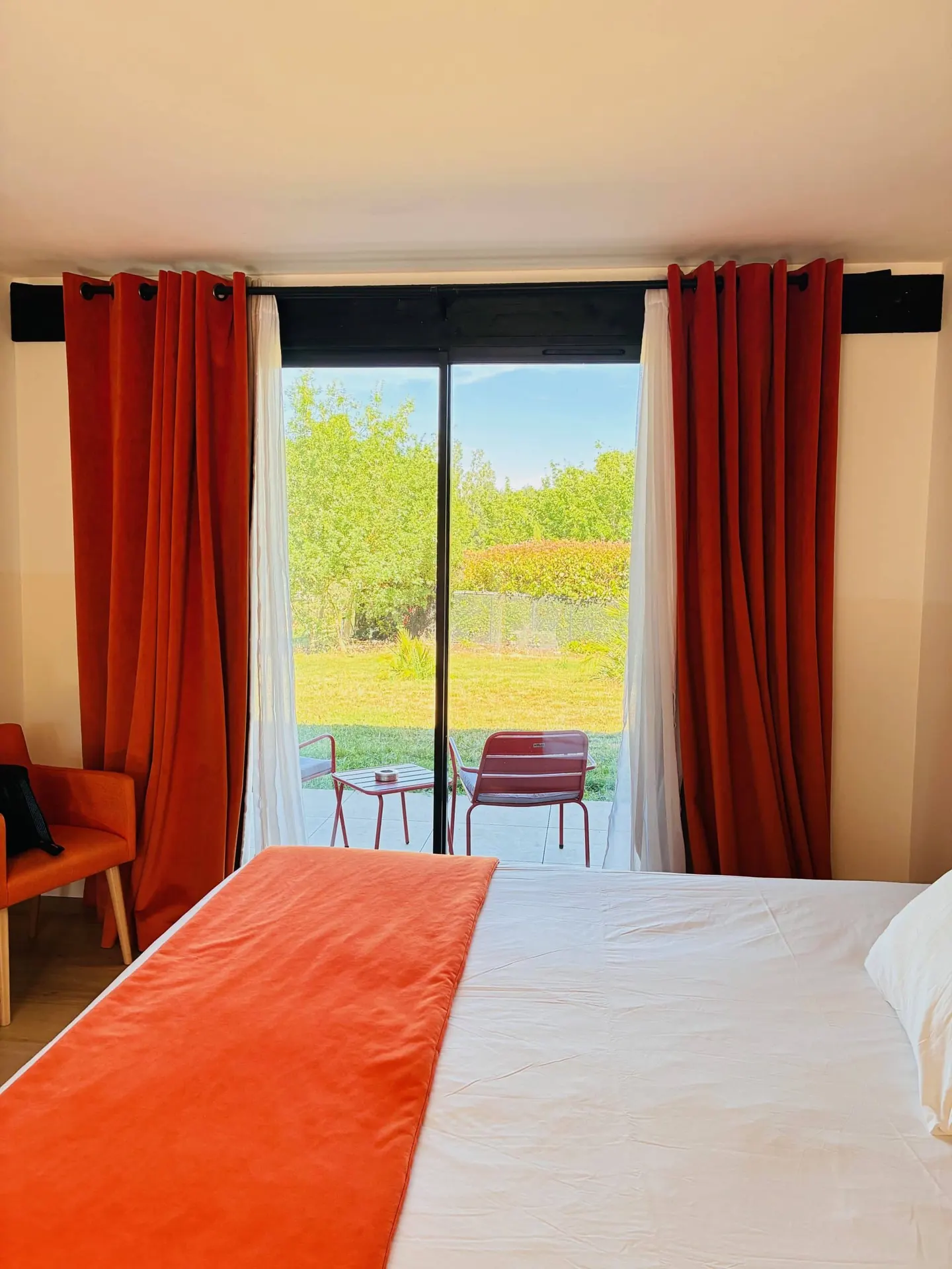 Chambre Premium aux rideaux rouges, baie vitrée sur le jardin
