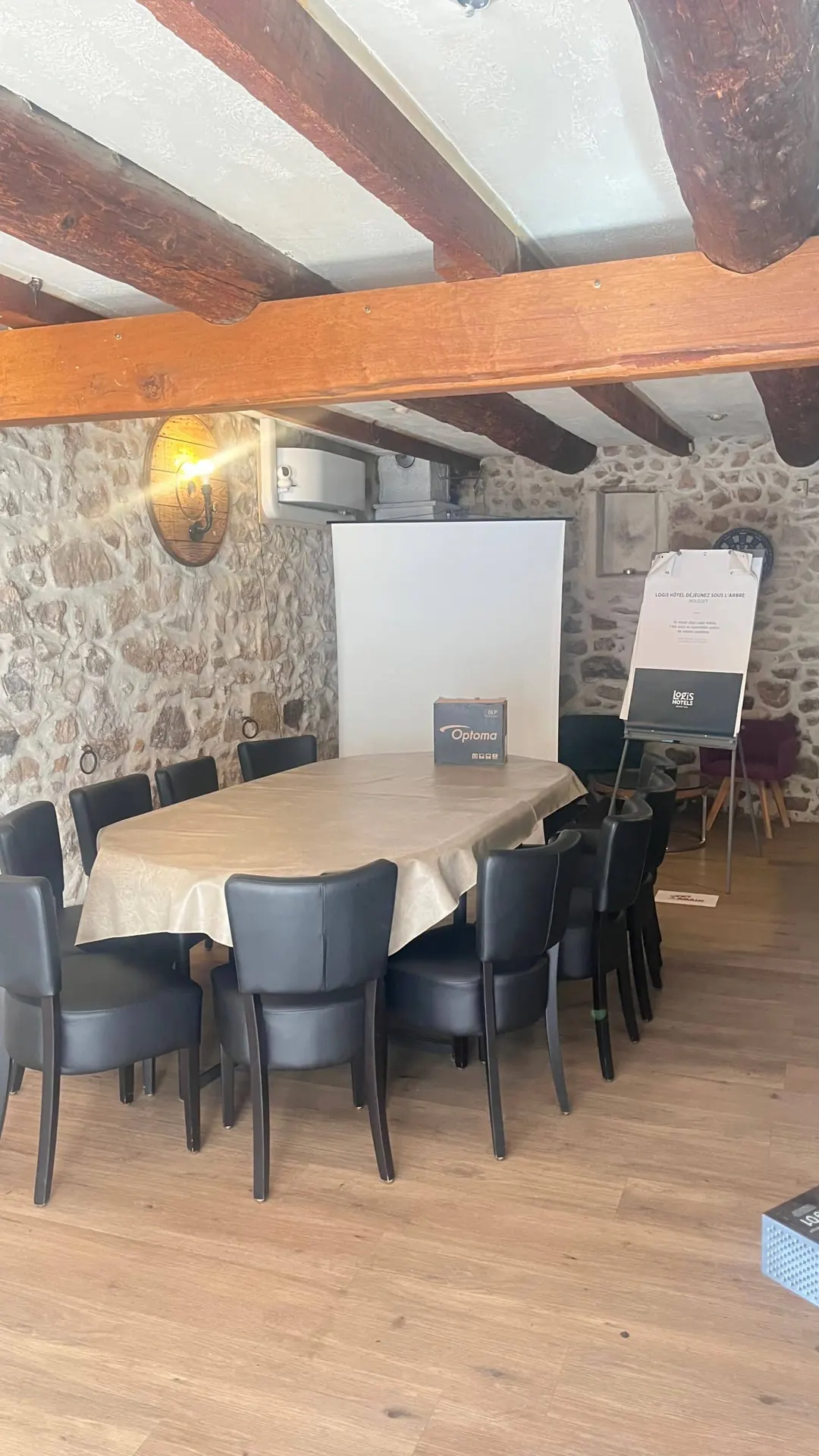 Salle de réunion aux murs en pierre, table et paperboard