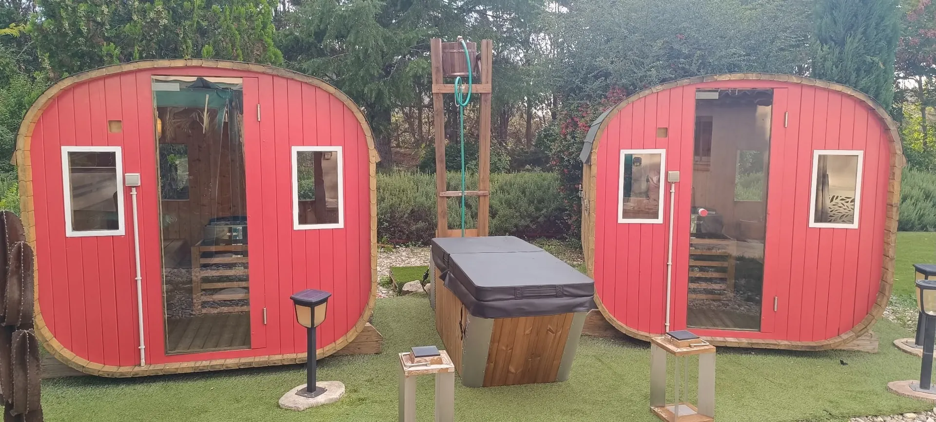 Deux saunas tonneaux rouges et le jacuzzi couvert dans le jardin du spa