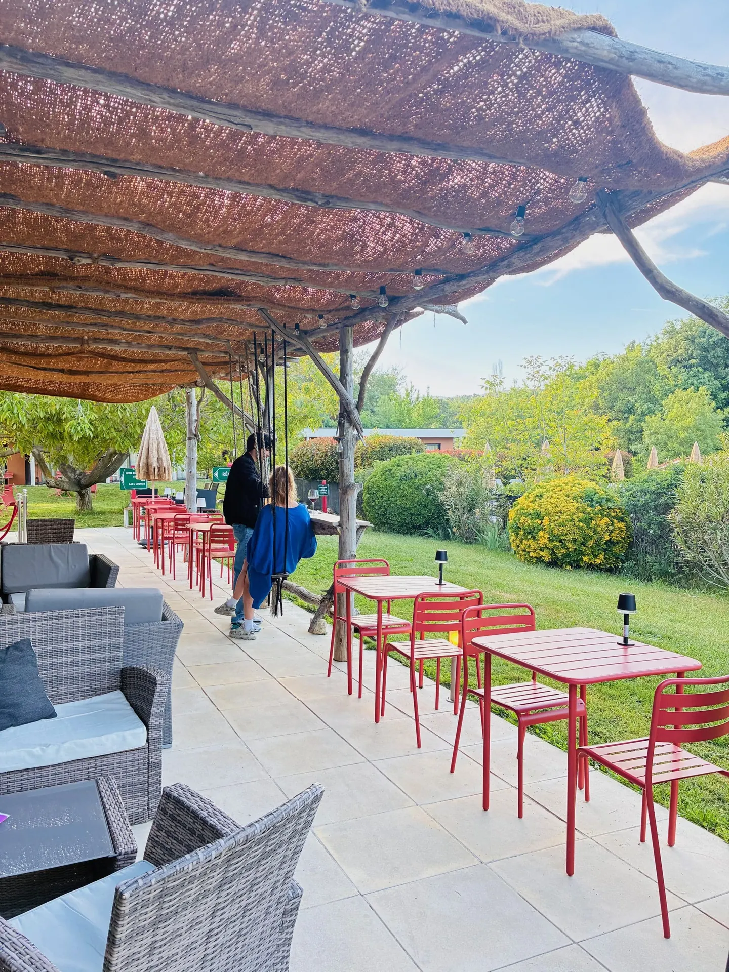 Clients sur la terrasse ombragée par la pergola en canisses